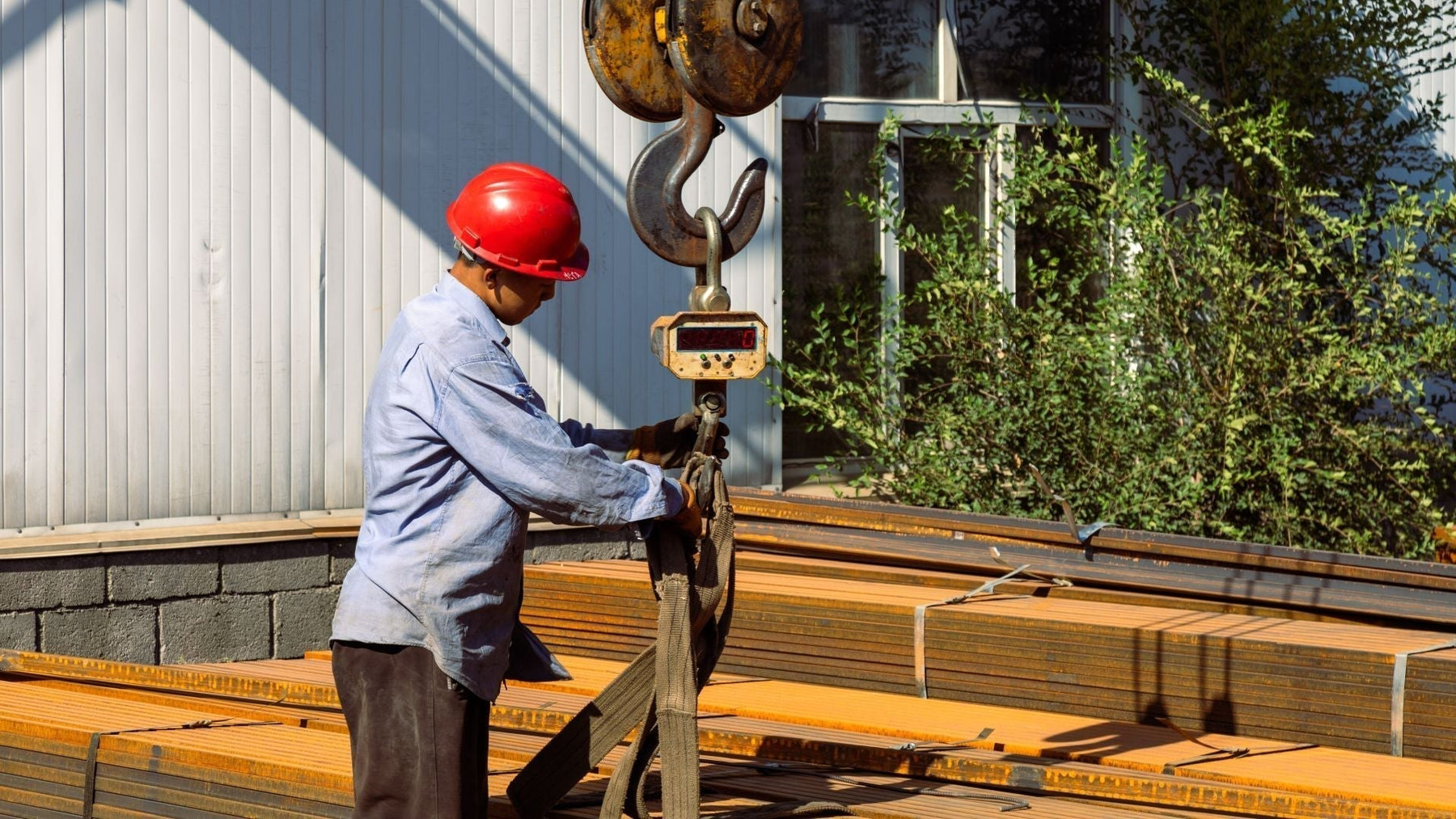 a heavy duty digital crane scale hanging from a hoist hook with a rigged load
