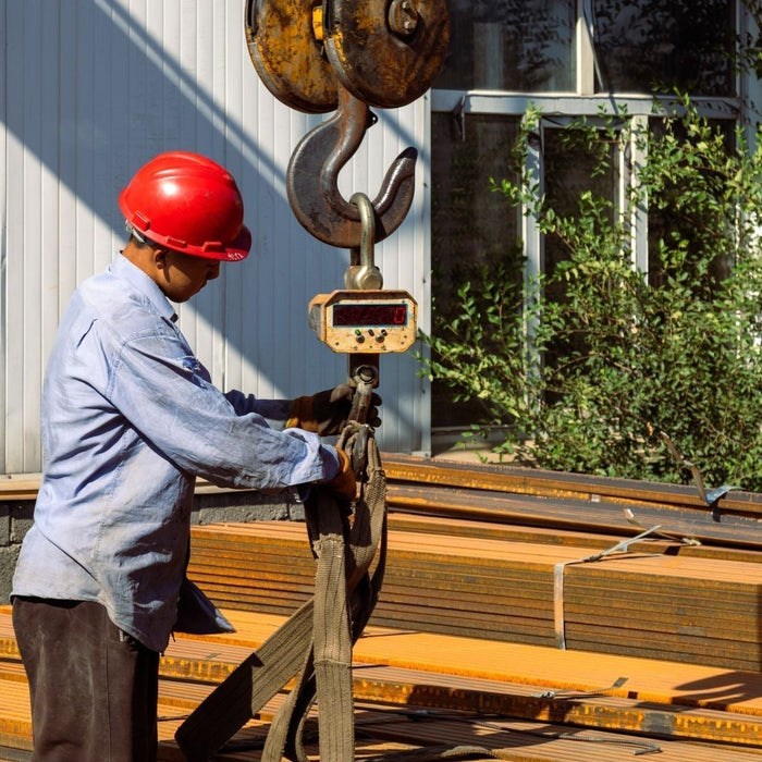 a heavy duty digital crane scale hanging from a hoist hook with a rigged load